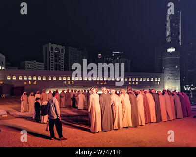 Emirati uomini eseguono il Yowla Emirati Arabi Uniti danza tradizionale in Al Hosn Foto Stock