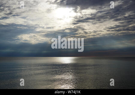 Cielo di tramonto sul mare. La luce del sole rende il suo modo attraverso le nuvole e il sole splende sopra la superficie dell'acqua. Lago di Michig Foto Stock