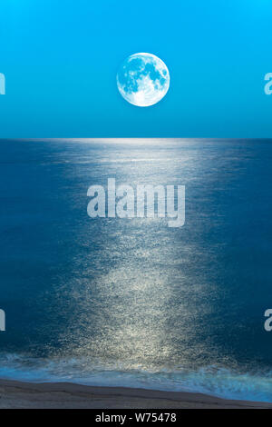 Luna piena riflettendo sulla riva del mare Foto Stock