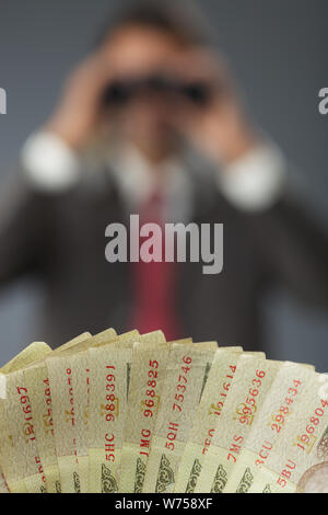 Uomo d'affari che guarda attraverso binocoli a soldi Foto Stock