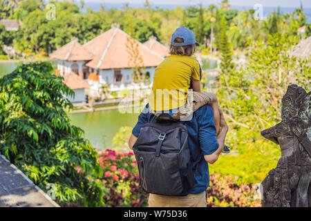 Papà e figlio in acqua Palace Soekasada Taman Ujung rovine sulla isola di Bali in Indonesia. Incredibile architettura antica. Viaggi e vacanze sfondo Foto Stock