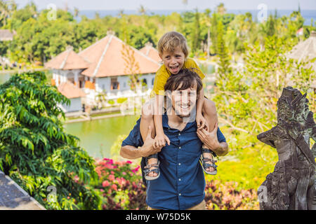 Papà e figlio in acqua Palace Soekasada Taman Ujung rovine sulla isola di Bali in Indonesia. Incredibile architettura antica. Viaggi e vacanze sfondo Foto Stock