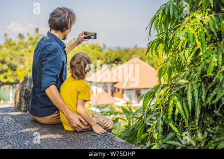 Papà e figlio in acqua Palace Soekasada Taman Ujung rovine sulla isola di Bali in Indonesia. Incredibile architettura antica. Viaggi e vacanze sfondo Foto Stock