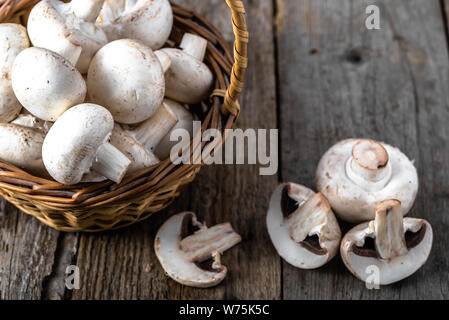 Fresco di funghi champignon in un cestino sul tavolo di legno, overhead Foto Stock