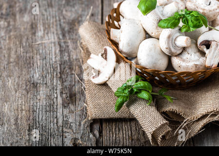 Fresco di funghi champignon in un cestino sul tavolo di legno, overhead Foto Stock
