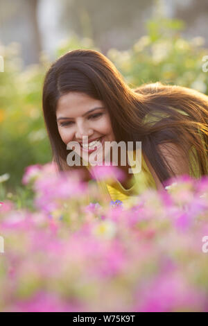 Indian giovane donna odore di fiore in un parco Foto Stock