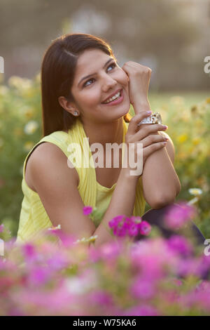 Giovane donna in un parco sogno ad occhi aperti Foto Stock