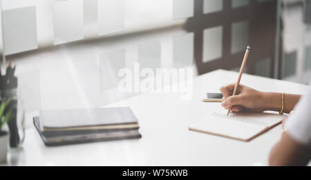 Vista ritagliata della donna la scrittura a mano sul suo portatile per il progetto di avvio Foto Stock