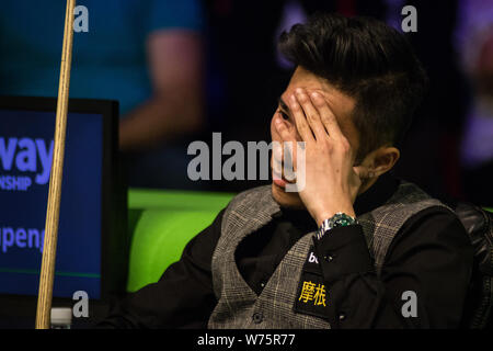 Cao Yupeng della Cina reagisce come egli orologi John Higgins della Scozia a giocare un colpo nella loro seconda partita durante il 2017 Betway campionato britannico sn Foto Stock