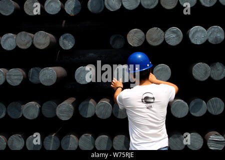 --FILE--un lavoratore cinese esamina una pila di acciaio grezzo in acciaio di un impianto di trasformazione in Liaocheng, est della Cina di provincia di Shandong, 8 giugno 2013. Mento Foto Stock