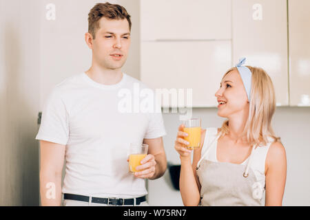 Immagine ravvicinata di bella bionda donna caucasica con il mio ragazzo tenendo il vetro con succo d'arancia appena spremuto, godendo di gustosa bevanda alla luce kitch Foto Stock