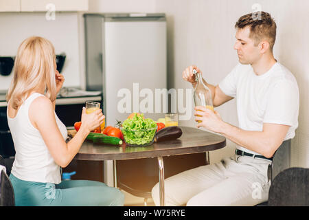 Maschi e femmine di vegetariani avente la prima colazione insieme a casa. Giovani caucasici donna felice e simpatico uomo sorridente avendo divertimento mentre mangia in cucina. Egli Foto Stock