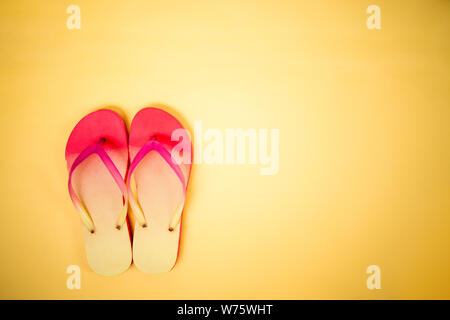 Coral Pink flip flop su sfondo giallo con copia spazio. Laici piana, orizzontale shot. Estate, vacanze, spiaggia, scarpe concetto. Foto Stock