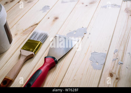 Vista dall'alto di un emulsionante con un pennello ed una spatola per stucco per applicazione su legno. Si tratta di un processo con una spatola. Spazio libero per pubblicità, testo. Foto Stock