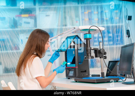 Lavoratore di sesso femminile nel controllo di resina LCD / DLP / SLA stampante 3D nel laboratorio di tecnologia Foto Stock