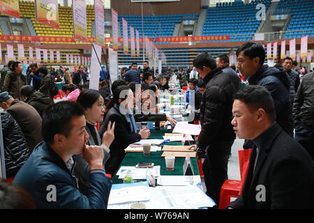 --FILE--Cinese in cerca di lavoro parla con intervistatori in cerca di occupazione a una fiera del lavoro in città Chizhou, est cinese della provincia di Anhui, 9 dicembre 2017. Foto Stock