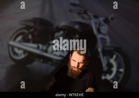 Maschio brutale biker guardando attraverso le diapositive della sua moto. Foto Stock