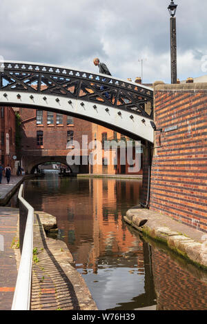 Un uomo si inclina in avanti come egli attraversa la barra di bloccaggio ponte a Gas Street Basin, Birmingham. La distanza è il Broad Street Tunnel, REGNO UNITO Foto Stock