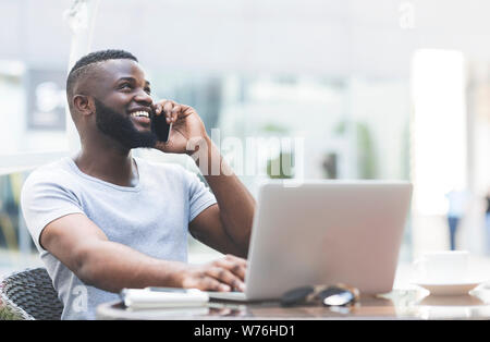 Giovane bello ragazzo africano lavorando sul computer portatile Foto Stock