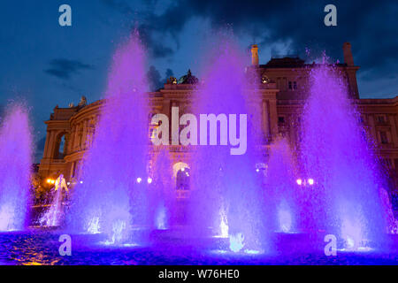 Ucraina Odessa, 11 giugno 2019. Vista laterale del national academic opera edificio e illuminate fontana al tramonto Foto Stock