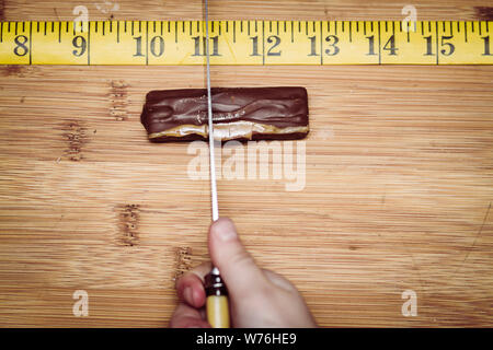 Una barra di cioccolato essendo tagliato in esatta porzioni uguali. Foto Stock