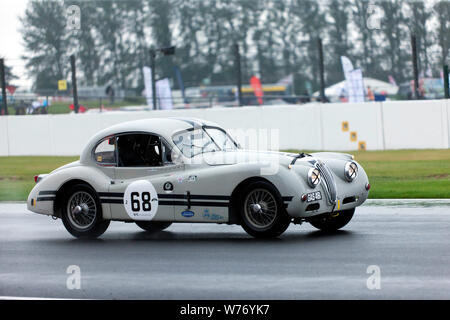 Un 1955, Jaguar XK 140 FHC, circa per entrare Brooklands, in concorrenza per il RAC Woodcote Trophy per pre '56 bolidi Foto Stock