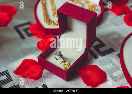 Anello rosso box .dorato anello di innesto in un cuore scatola sagomata e rose Foto Stock