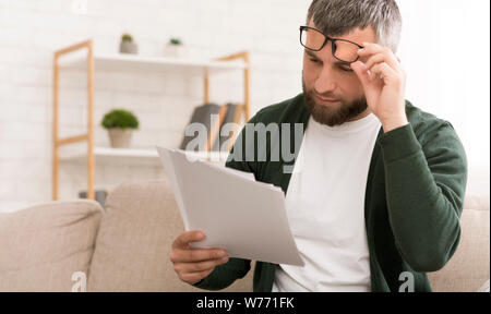 Di mezza età uomo caucasico la lettura di carte a casa Foto Stock
