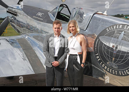 Taron Egerton e Rosamund Pike con un restaurato MK IX Spitfire a Goodwood aerodromo. Argento IWC Spitfire piloti Matt Jones e Steve Boultbee Brooks sta cercando di battere la MK IX Spitfire denominato 'Silver Spitfire" in tutto il mondo nella prima circumnavigazione del globo da parte di un piano di spitfire. Foto Stock