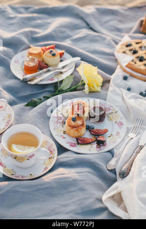 Splendido picnic con pancake, marmellata, American Pie e tè sul tramonto al mare. Foto Stock