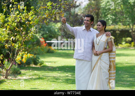 South Indian man showing something to his wife in a park Stock Photo