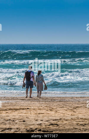 I turisti in piedi sul litorale affacciato sul mare su Fistral Beach in Newquay in Cornovaglia. Foto Stock