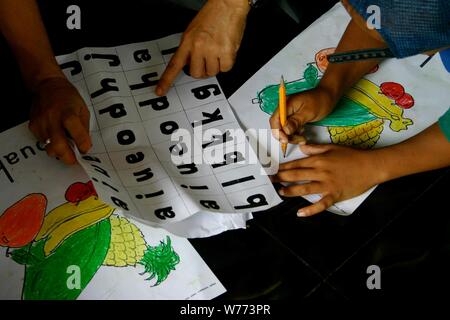 Bogor, West Java, Indonesia - Luglio 2019 : una immagine ravvicinata di elementare bambini processo di insegnamento con alfabeto e disegni in una classe di volontariato. Foto Stock