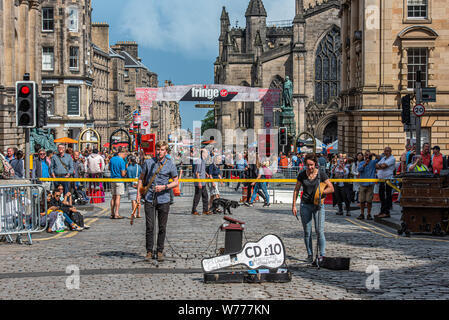 Edimburgo, Scozia, Regno Unito. 4° agosto 2019. Gli artisti di strada e attori di intrattenere il pubblico e pubblicizzare la loro mostra in Edinburgh Royal Mile a Foto Stock
