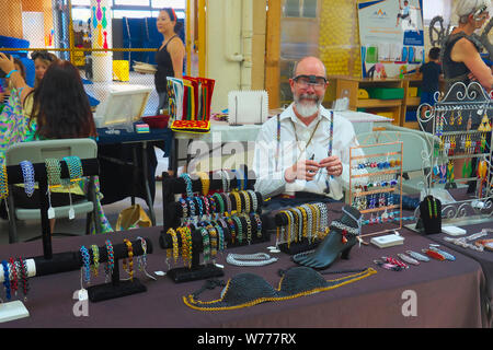 Un vender di gioielleria maschile ad una fiera artigianale che crea gioielli a catena. Foto Stock