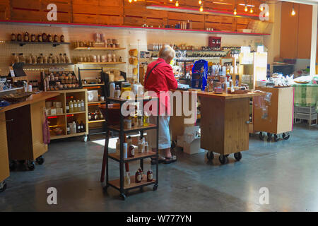 Donna bionda in rosso cappotto di shopping in una vasca da bagno shop presso il River Market, New Westminster, British Columbia, Canada. Foto Stock