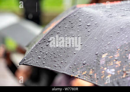 Giorno di pioggia, Heavy Rain in città, gocce sulla superficie di Ombrello nero, persone con ombrelloni durante la tempesta Foto Stock