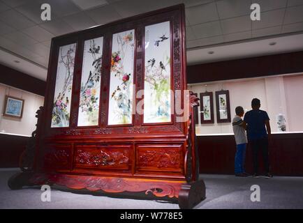 (190805) -- NANCHANG, e il Agosto 5, 2019 (Xinhua) -- Mao Guanghui (L) introduce le sue creazioni per un visitatore presso la sala delle esposizioni di una ceramica Research Institute di Jingdezhen, Cina orientale della provincia di Jiangxi, 31 luglio 2019. Mao Guanghui, un 56-anno-vecchio maestro senior di arti e mestieri nella provincia di Jiangxi, si dedica alla pittura su porcellana fin dall'età di 13. Come una terza generazione di discepolo di Deng Bishan (1874-1930), una delle 'Otto Amici di Zhushan', un gruppo di artigiani di Jingdezhen ampiamente noti per le loro innovazioni in porcellana dipinto, Mao ha ereditato non solo la capacità ma anche t Foto Stock