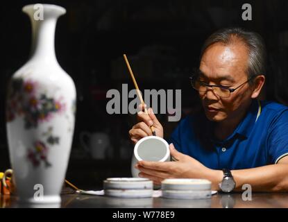 (190805) -- NANCHANG, e il Agosto 5, 2019 (Xinhua) -- Mao Guanghui funziona su un pezzo di porcellana nel suo studio di Jingdezhen, Cina orientale della provincia di Jiangxi, e il Agosto 1, 2019. Mao Guanghui, un 56-anno-vecchio maestro senior di arti e mestieri nella provincia di Jiangxi, si dedica alla pittura su porcellana fin dall'età di 13. Come una terza generazione di discepolo di Deng Bishan (1874-1930), una delle 'Otto Amici di Zhushan', un gruppo di artigiani di Jingdezhen ampiamente noti per le loro innovazioni in porcellana dipinto, Mao ha ereditato non solo la capacità ma anche la tecnica di creazione di pittura su porcellana pezzi. Il Foto Stock