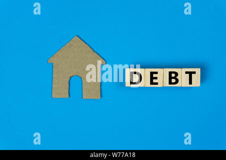 Home Prestito, ipoteca, home concetto di debito. Una piccola casa carta tagliata modello con blocco di legno su sfondo blu. Immobiliare di passività. Proprietà investme Foto Stock