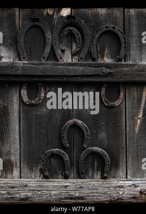 Ferro di cavallo rustico in legno vintage background. Vecchio ferro di cavallo appeso sulla porta di legno nel villaggio - simbolo di fortuna Foto Stock