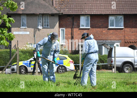 Gli ufficiali di polizia ricerca Waltheof Giardini in Tottenham, nord di Londra dopo un 89-anno-vecchia donna è stato trovato ucciso nella sua casa (dietro). Foto Stock