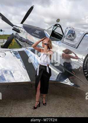 Rosamund Pike con un restaurato MK IX Spitfire a Goodwood aerodromo. IWC Schaffhausen argento Spitfire piloti Matt Jones e Steve Boultbee Brooks sta cercando di battere la MK IX Spitfire denominato 'Silver Spitfire" in tutto il mondo nella prima circumnavigazione del globo da parte di un piano di spitfire. Foto Stock