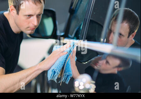 L'uomo è strofinando con un panno il corpo di una brillante auto. Foto Stock