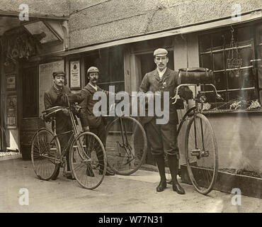 Vintage fotografia di ciclisti in stile Vittoriano al di fuori di una grande stazione ferroviaria occidentale, con la bicicletta e Penny Farthing, secolo XIX Foto Stock