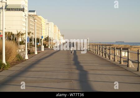 BREZZA OCEANICA: Un uomo anziano fa una piacevole passeggiata mattutina lungo la splendida passeggiata sulla spiaggia della Virginia. Foto Stock