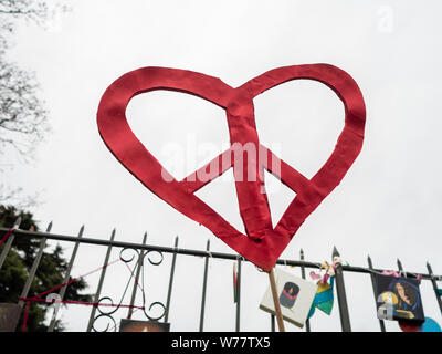 Rosso cuore di pace fatta di carta contro un cielo grigio alla moschea memorial di tiro a Christchurch, Nuova Zelanda Foto Stock