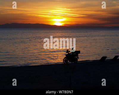 Silhouette con motorsycle sulla spiaggia al tramonto Foto Stock