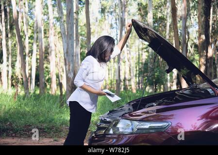 Donna asiatica chiamando repairman o assicurazione personale per fissare il motore di una macchina problema su una strada locale - Persone con problema alla vettura in concetto di trasporto Foto Stock