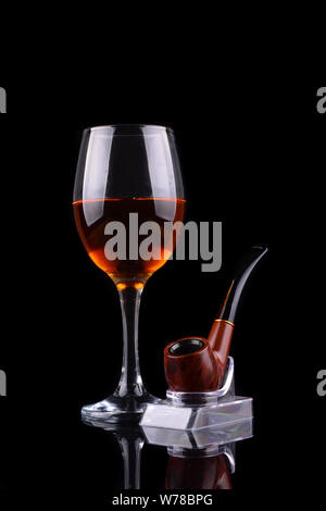 Bicchiere da vino e tubo di fumo su sfondo nero Foto Stock